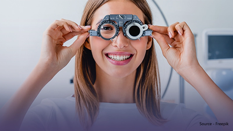 A smiling woman holding trial lens frames to her eyes, symbolising a positive eye test experience and the process of finding the right prescription.