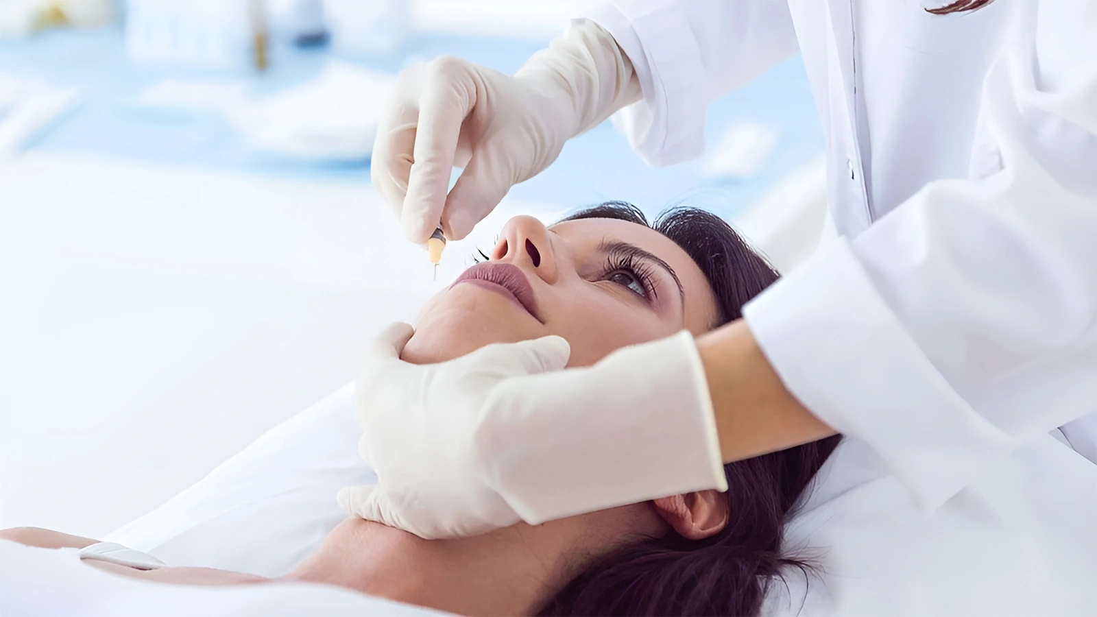 A medical professional in white gloves administering a facial injection to a woman, demonstrating a treatment option for under-eye discolouration.